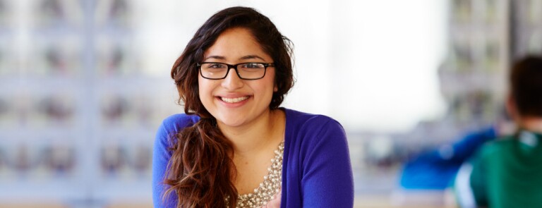 Marquette graduate student smiling while wearing a blue sweater and pearls