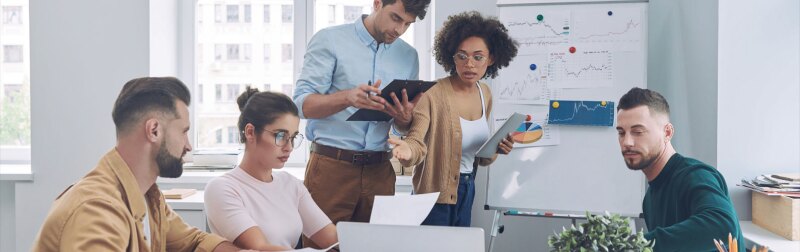 Group of confident young people in smart casual wear discussing business while having meeting in office.