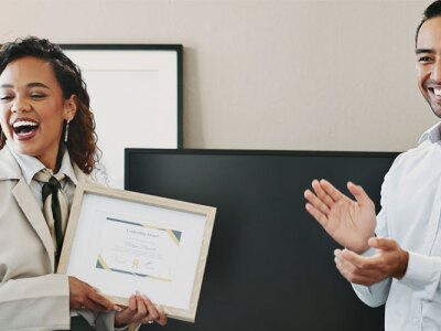 A joyful businesswoman is awarded the "Leadership Award" certificate in an office to show appreciation from the company.