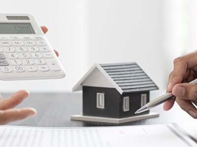 Toy house and calculator being used in real estate finance discussion