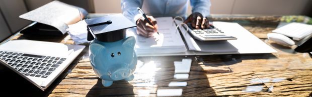Peron using calculator on a desk next to a piggy bank