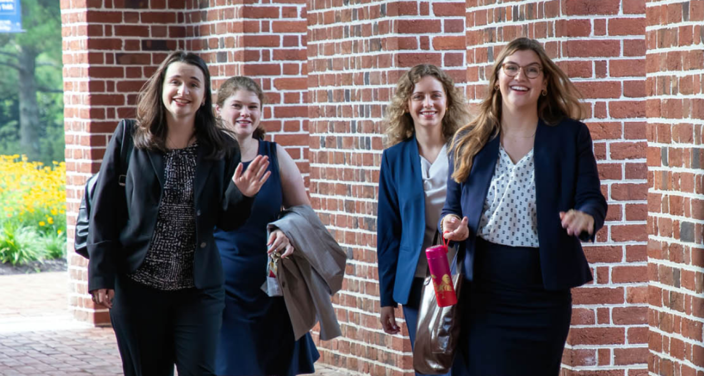 Four female William & Mary students walking on brick walkway on campus