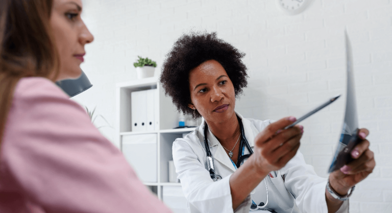 Female doctor explaining x-ray to female patient in office