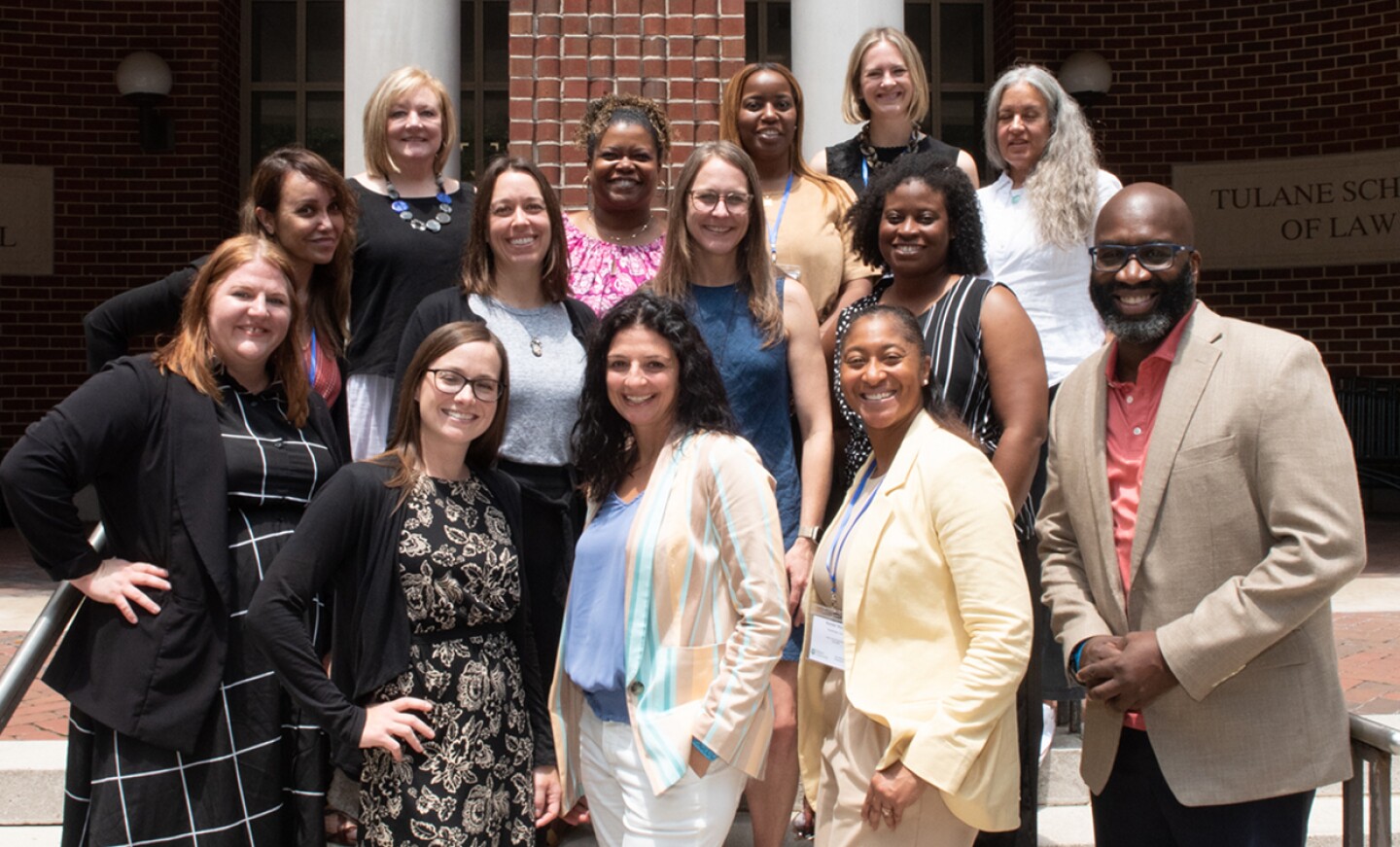 Group of smiling Tulane students standing outside building on campus