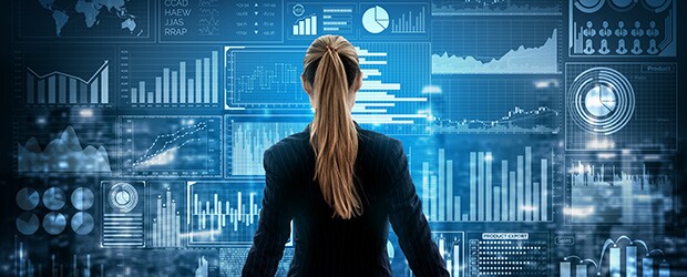 A businesswoman in a suit reviews business analyst job outlook data on a large screen.