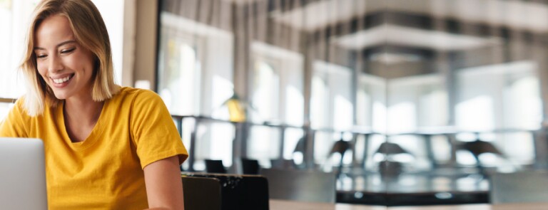 Woman in yellow shirt works on laptop