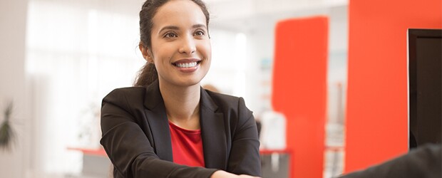woman in red shirt black jacket shaking hands red wall to the right