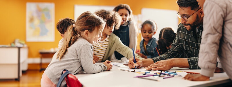 A teacher and young students work on an art project together