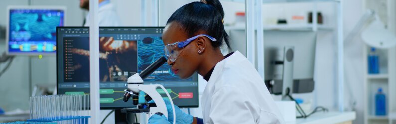 woman looking through microscope in laboratory