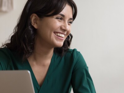 Two women having a conversation seated at desk in workplace.