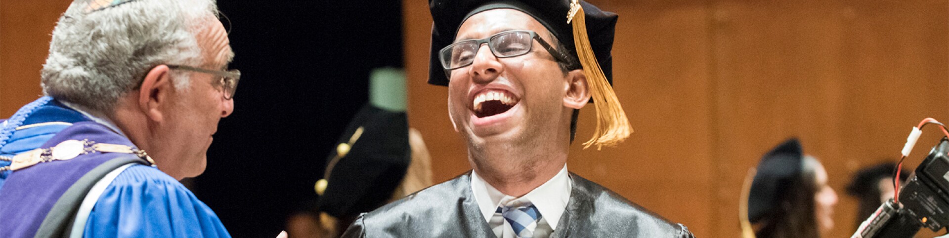 man with a big smile at graduation ceremony
