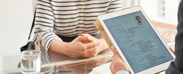 Businessman reading resume of woman on his digital tablet during an interview