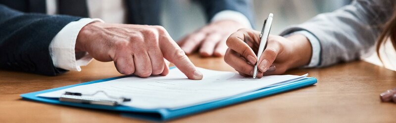 A person signing a document on a conference table