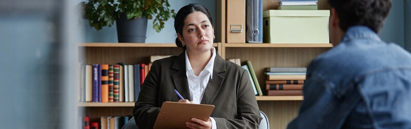 Female counselor listening attentively to teenage boy during counseling session