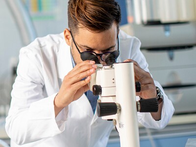 Scientists working with binocular microscope in the material science lab