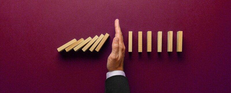 Insurance, hand stopping a series of dominos from falling