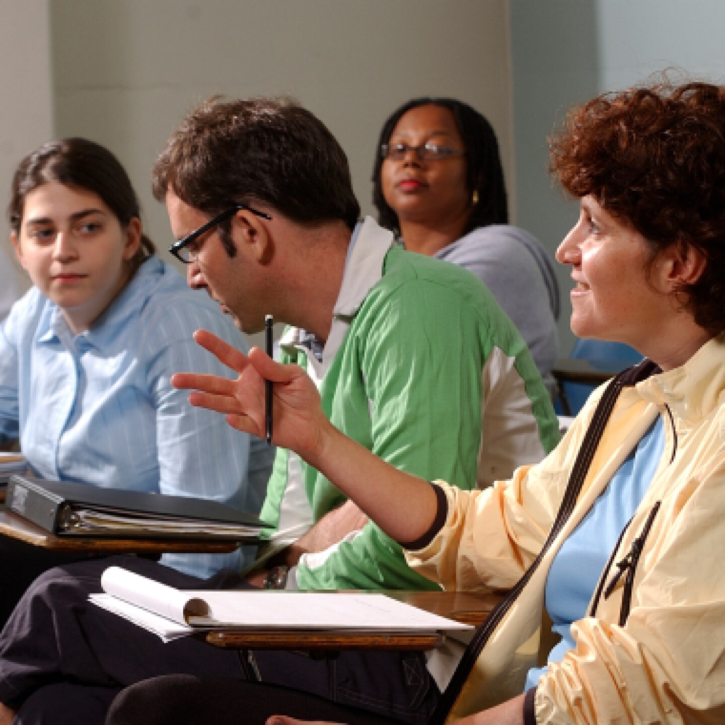 Group of diverse Yeshiva University students talking in classroom.