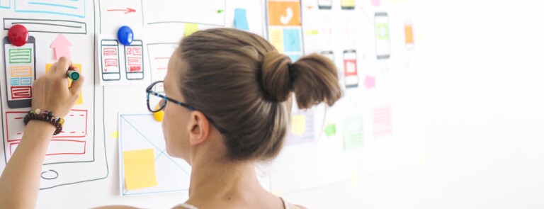 UXD Professional draws on low fidelity wireframes and sticky notes on a whiteboard
