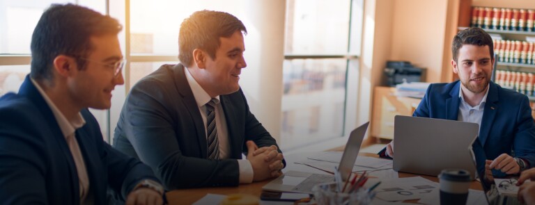 a group of professional conduct a meeting in a law office while working on laptops