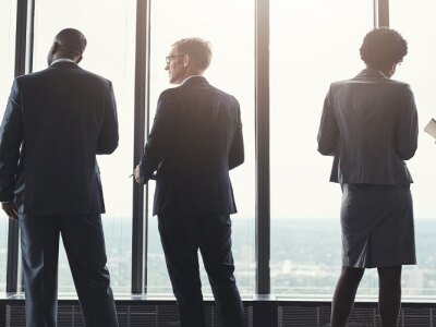 Business people, discussion and standing by window in boardroom with city view for career in real estate.