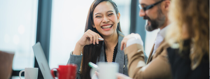 A young business professional woman laughs while collaborating with colleagues