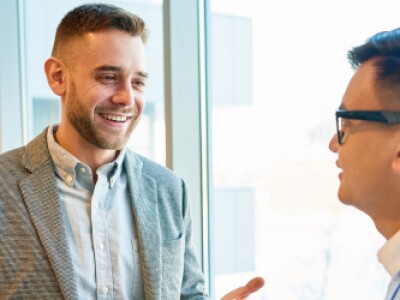 two men having a conversation next to a window