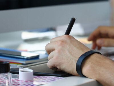 Male instructional designer arm holding graphic pad pen working on project.