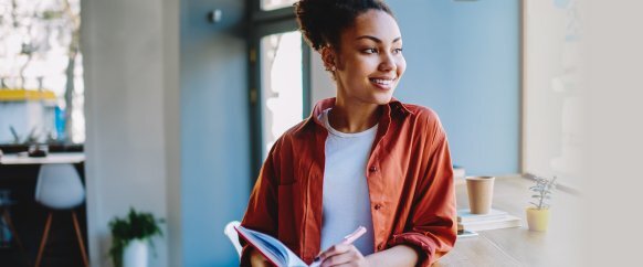 woman-with-hair-up-in-orange-shirt-smiling-looking-to-side-in-blue-room