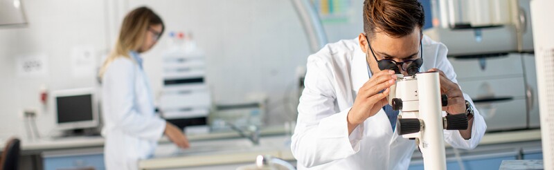 Scientists working with binocular microscope in the material science lab