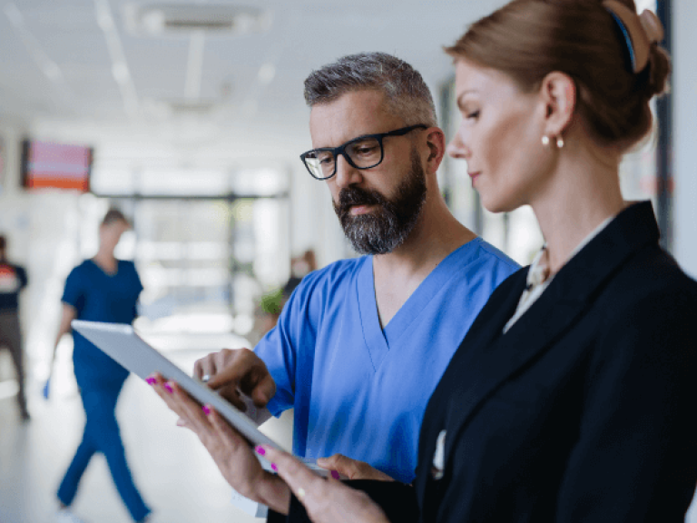 Male nurse consulting with female healthcare compliance officer using tablet