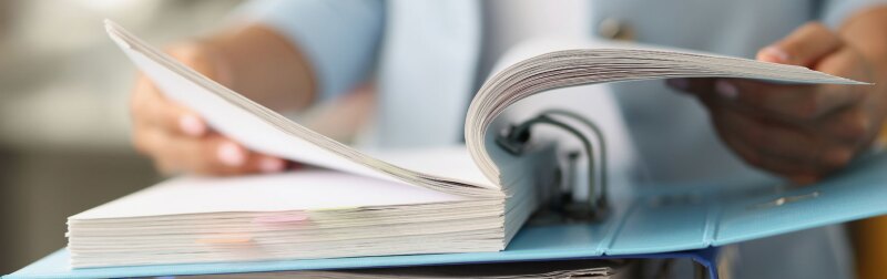 Closeup of woman examining finance regulation documentation in folder.