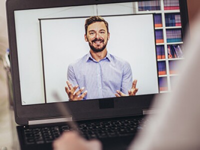 Image of a smiling, bearded man on a laptop screen