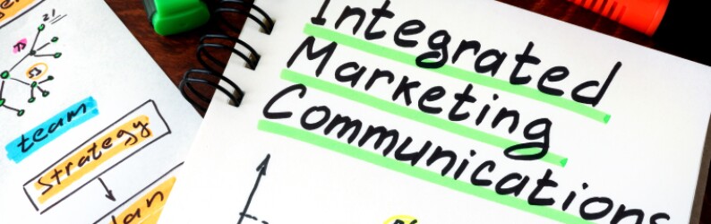 Integrated marketing communication is written in marker on a notebook, with the other words team and strategy