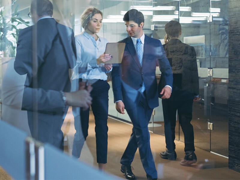 Man and woman walking office environment looking at tablet