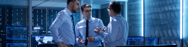 Three professionals in discussion in operations room