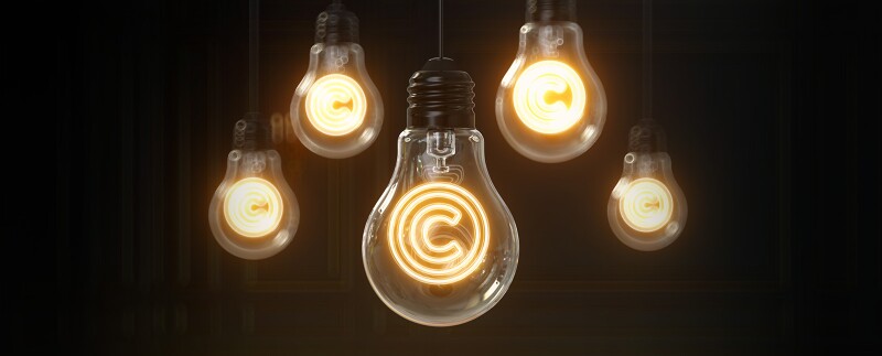 Copyright icon glowing inside of a light bulb hanging from the ceiling