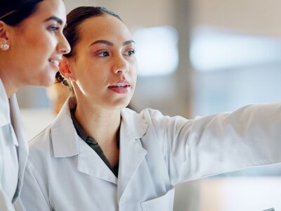 Female health professionals on computer for laboratory advice, medical research and night planning.