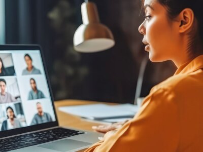 Female social worker sits at a computer while communicating with her team during a video conference call.