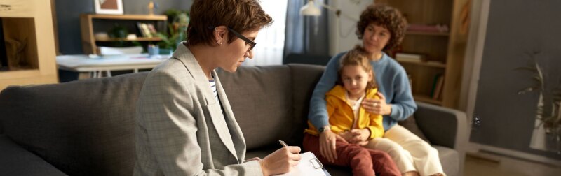 Social worker taking notes during home visit with mom and child