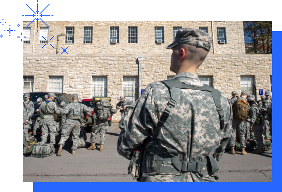 A group of military service men and women stand outside the KU campus building.