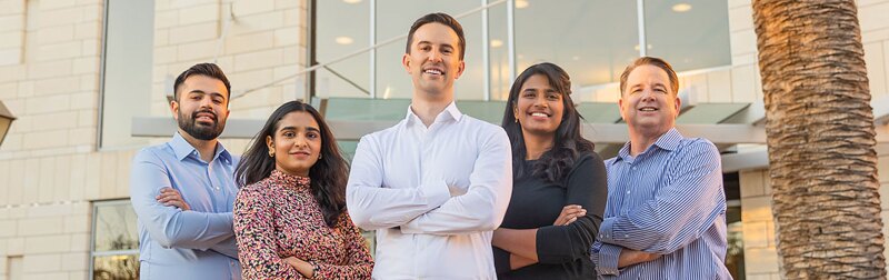 A group of SCU Leavey student stand outside in front of the campus commons building.