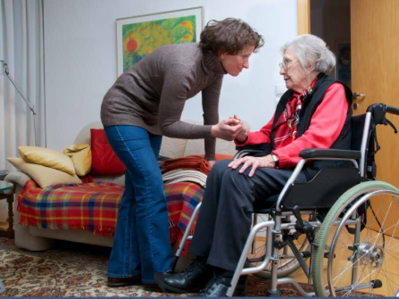 social worker holding hand of an elderly woman in wheelchair