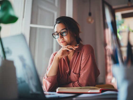 Beautiful businesswoman sitting at table opposite laptop in work
