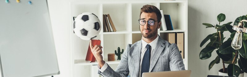 A young business sports agent spinning a soccer ball on his finger in the workplace.