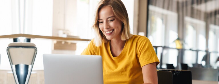 Woman in yellow shirt works on laptop