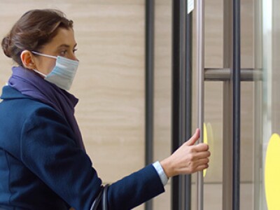 Commercial real estate trends post-COVID with side view of businesswoman entering office building