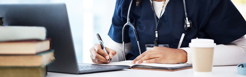 A nursing student studying, surrounded by books and a laptop