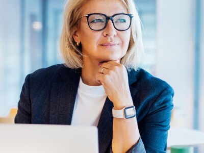 Successful business woman ponders the benefits of entrepreneurship while on a computer in her office.