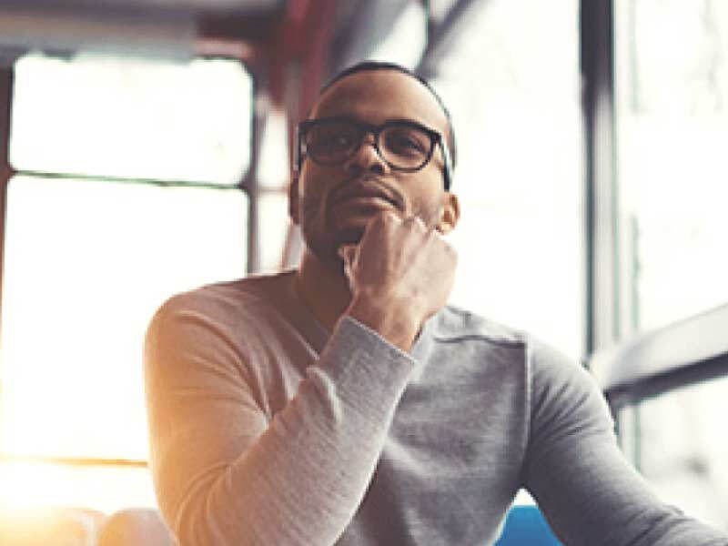 Man in glasses thinking with hand on chin