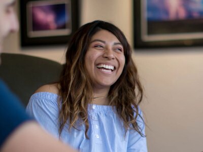 A group of MBA students sit in a lobby while having a friendly conversation.